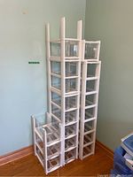 Full view of three stacked modular storage drawer units against a wall. Clear drawers supported in white plastic frames. Total 20 drawers visible.