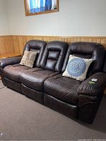 Full front view of brown leather reclining sofa with two throw pillows