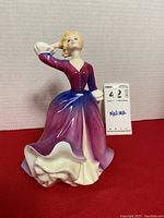 Front view of the Royal Doulton 'Melissa' figurine in purple and pink dress with hand on head.