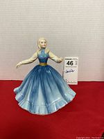 Front view of the porcelain figurine showing the detailed face and full blue dress with gold belt.