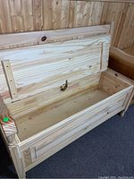 Close-up of the opened hinged seat showing the storage compartment inside the wooden Deacons bench.