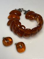 Antique amber bracelet and matching cufflinks on flat surface showing color and shape of pieces.