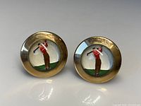 Front view of the pair of antique gilt-metal cufflinks with Essex crystal featuring miniature golfer figures inside.