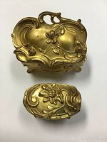 Two gilt metal jewelry caskets with ornate floral design, closed