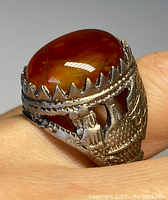 Close-up side view of the ring showing the oval carnelian stone with the serrated bezel and detailed silver filigree work on the band.