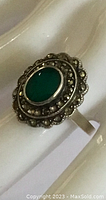Close-up front angle of antique sterling silver ring with chrysoprase stone and marcasite accents on scalloped setting.