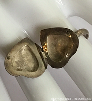 Close-up of open locket heart-shaped ring showing hollow compartment inside
