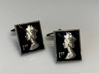Front view of the pair of square cufflinks featuring a black enamel background with a raised silver queen's profile and '1st' engraving.