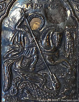 Close-up detail of the embossed St. George figure on horseback with painted face, showing spear and dragon detail.