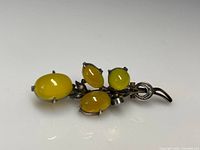 Top view of the antique sterling silver floral brooch with smooth yellow moonstones and seed pearl details.