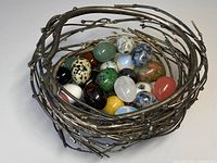 Overall view of silver birds nest sculpture holding assorted genuine stone geode eggs, showing nest shape and varying colors of eggs.