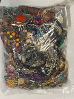 Front view of sealed bag showing mixed jewelry items including colorful beads, chains, and metal pieces.