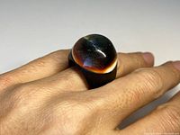 Chunky antique ring worn on finger showing large domed operculum centerpiece with brown, black, and cream color bands and dark baleen band.