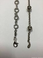Close-up of lobster clasp and linked circular ring design on one bracelet.