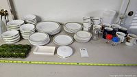 Full lot overview showing multiple plates, bowls, mugs, cups and a green ceramic egg tray.