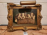 Full front view of framed art showing puppies in basket with light attached above.