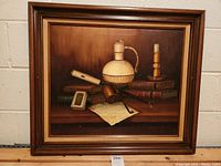 Oil painting of still life with books, pipe, ceramic bottle, candle, and paper. Framed in wood.