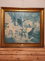 Full view of framed painting showing outdoor scene with man at table, chairs, tree, and hammock.
