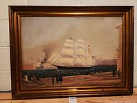 Full view of the framed oil painting depicting a ship in a harbor scene with figures on shore, showing the overall condition and subject matter of the artwork.