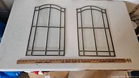 Two glass wall hangings displayed side by side with measuring stick, showing size and design.