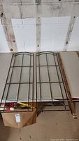 Two glass panels with metal grid frames and hooks shown on table next to measuring stick indicating length around 34.5 inches.