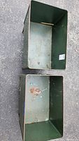 Top view showing interior condition of both green metal containers with rust and paint wear