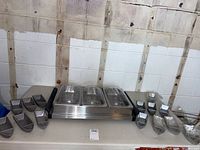 Wide shot showing all 14 shrimp cocktail boats arranged on table beside Wilton 3-pan stainless steel chafing warming tray with lids.