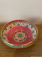 Top view of the antique Minton bowl showing raspberry interior with floral hexagonal center and green leaf border.