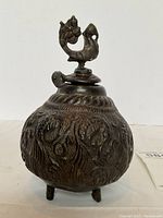 Front view of bronze censer showing body relief and bird finial