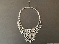 Full front view of the necklace laid flat on dark background