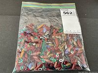 Clear resealable bag of mixed red faceted gems and multicolored navette cabochons
