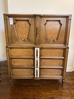 Front view showing two-door upper cabinet and six lower drawers with burl veneer panels and brass hardware