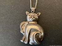 Front view of the sterling silver cat pendant showing detailed cat face and curled tail with chain attached.