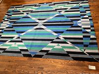 Full view of rectangular abstract geometric rug laid on hardwood floor