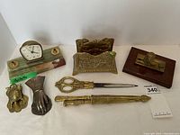 Overview of vintage brass desk accessories including clock, scissors, letter holders and decorative items.