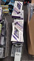 Photo showing multiple boxes of Burst Out earbuds in purple-and-white packaging stacked together.