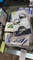 Photo showing Burst Out stereo wireless headset earbuds in packaging with ear hooks and black/green design.