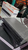 Six black HIK Vision DS-7600 NVR units stacked horizontally with vent holes and front panel visible. A HIK Vision product box is shown behind the units.