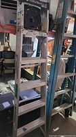 Full view of the 6-foot aluminum step ladder showing rungs and side rails, in storage setting.