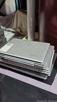 Stack of laptops with Lenovo branding on top, closed laptops