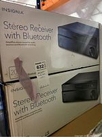 Two boxed Insignia Bluetooth stereo receivers stacked on shelf, showing box design and size.