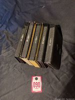 Five black textured proof coin cases with years 1975, 1976, 1977, 1978, and 1979 on spines.