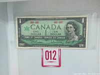 Front side of the 1967 Centennial Canadian One Dollar bill displaying Queen Elizabeth II portrait and centennial dates.