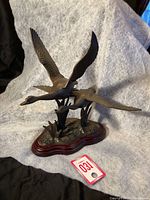 Overall view of the two flying geese metal sculpture on a wood base.