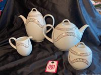 Full set of four pieces showing coffee pot, teapot, creamer, and sugar bowl with matching floral and gold trim pattern.