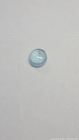 Top view photo of the oval sky blue aquamarine cabochon gemstone showing its smooth domed surface and light blue tone.