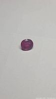Oval cut ruby gemstone on white background showing facets, color, and clarity