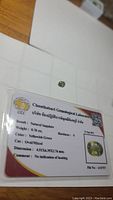 Photo of natural green yellow sapphire gemstone with Chanthaburi Gemological Laboratory certificate. Shows detailed stone and certification card with weight, color, cut and dimensions.