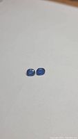 Pair of small deep blue oval kyanite gemstones on white background