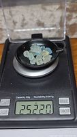 Natural blue-green aquamarine and yellow heliodor beryl crystals weighed on digital scale showing 25.220 carats total weight